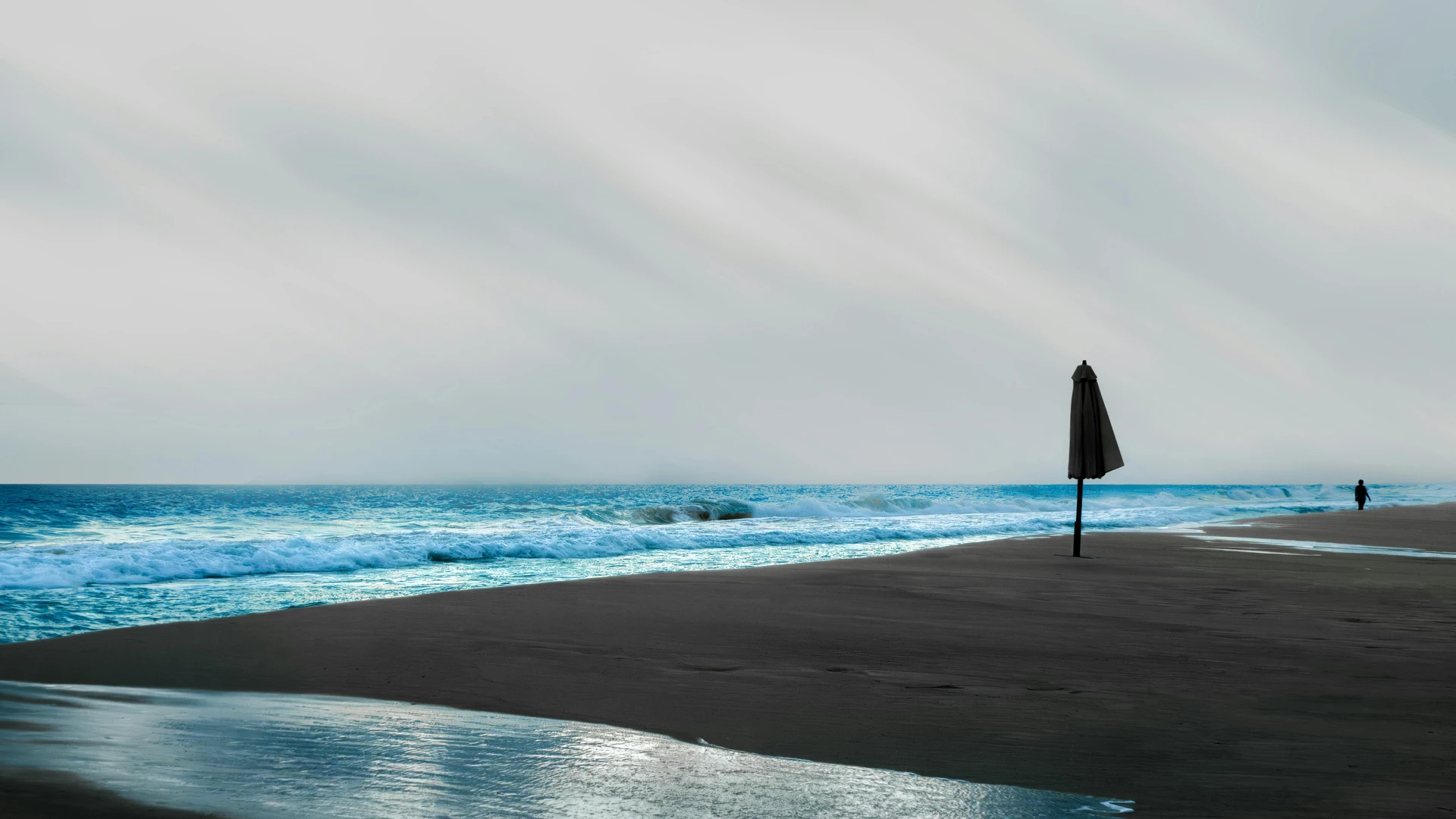 Alexandria, Egypt - Tranquil beach scene on alexandria's north coast, featuring waves, sand, and a solitary umbrella.