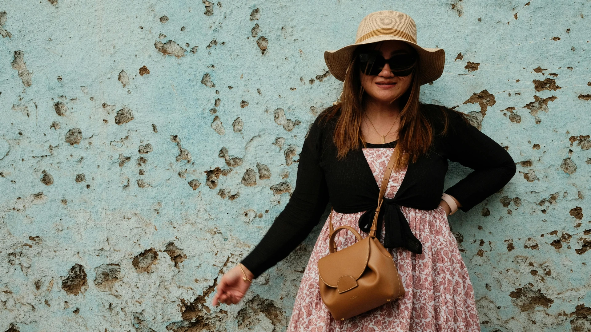 Aswan, Egypt - Fashionable woman in sunhat and sunglasses posing against a textured wall in aswan, egypt.