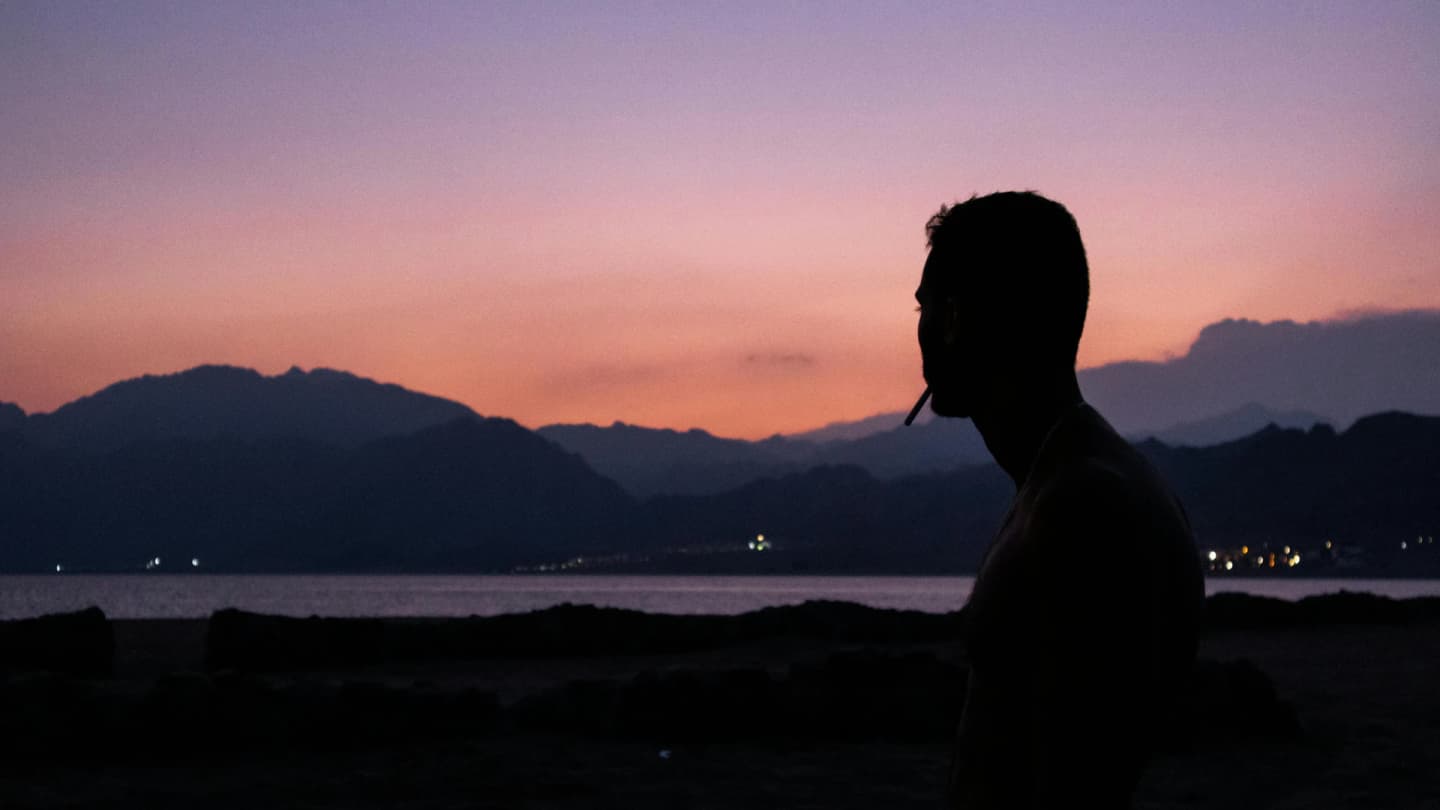 Dahab, Egypt - Silhouette of a man smoking against a colorful twilight sky in dahab, egypt.
