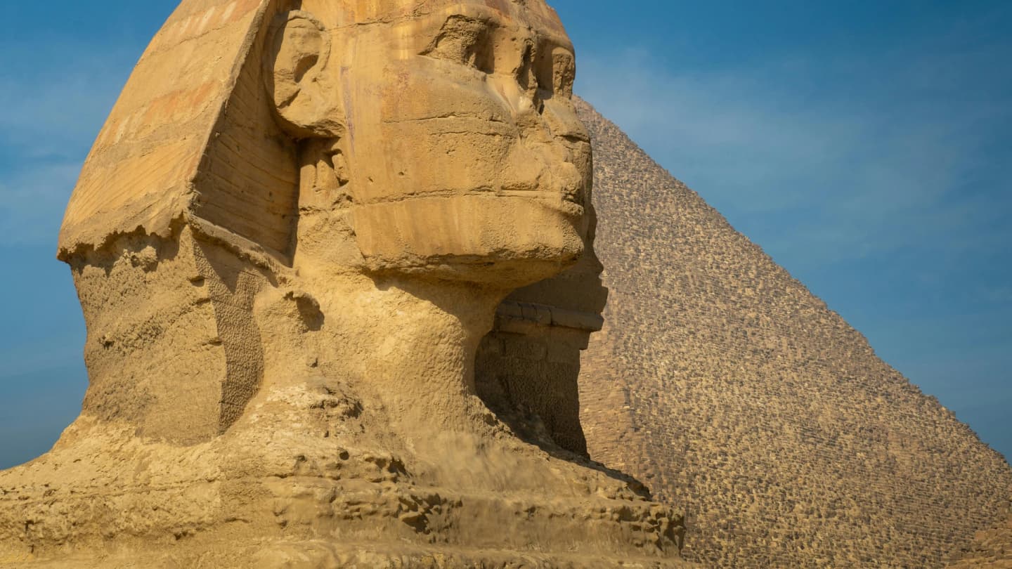 Dahab, Egypt - Iconic view of the great sphinx of giza beside a pyramid under a clear blue sky.