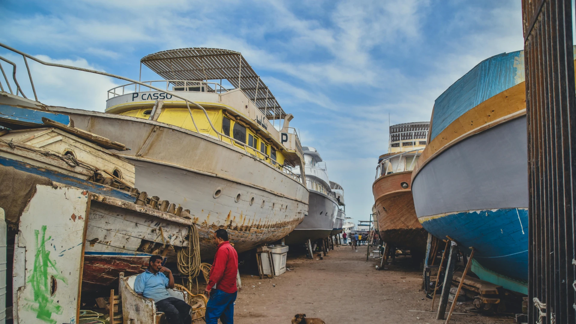 Hurghada, Egypt - Docked boats in a repair yard in hurghada, egypt. industrial maritime scene with people.