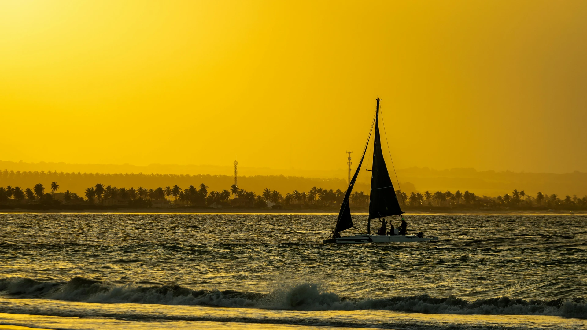 Hurghada, Egypt - Sailboat on the ocean against a stunning yellow sunset near the palm-lined shore of cabedelo, brazil.