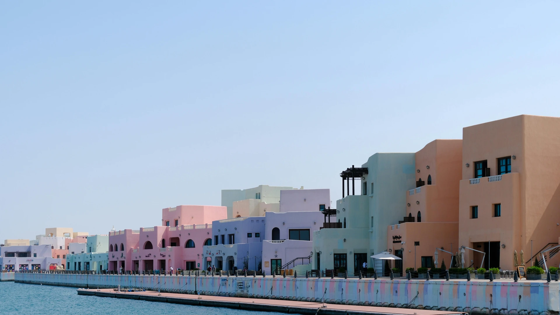 Hurghada, Egypt - Vibrant pastel buildings line a waterfront under a bright blue sky, creating a scenic view.