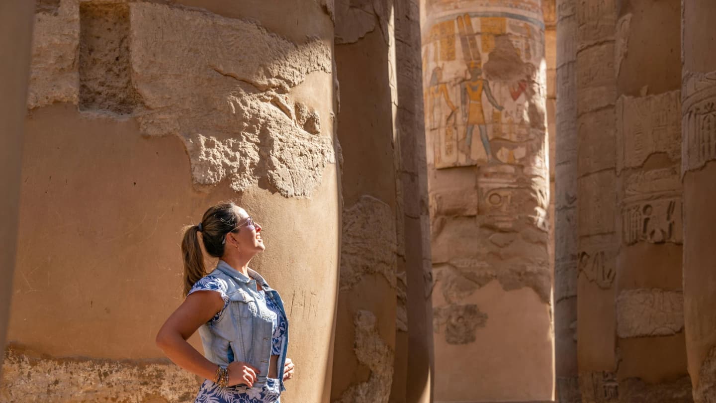 Marsa Alam, Egypt - Woman in luxor temple admiring ancient carved columns in sunlight.