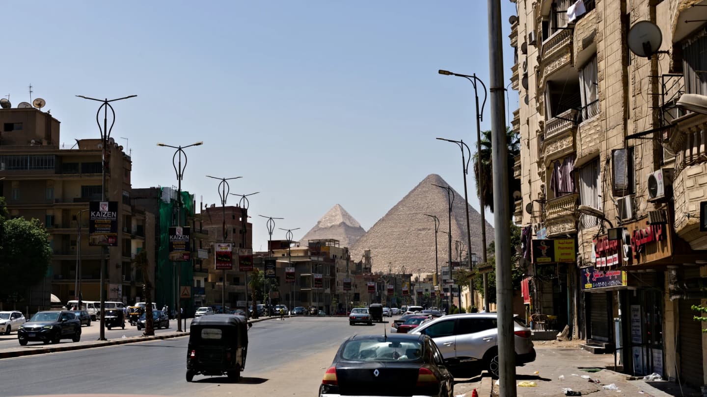 Safaga, Egypt - Pyramids visible over buildings and street traffic