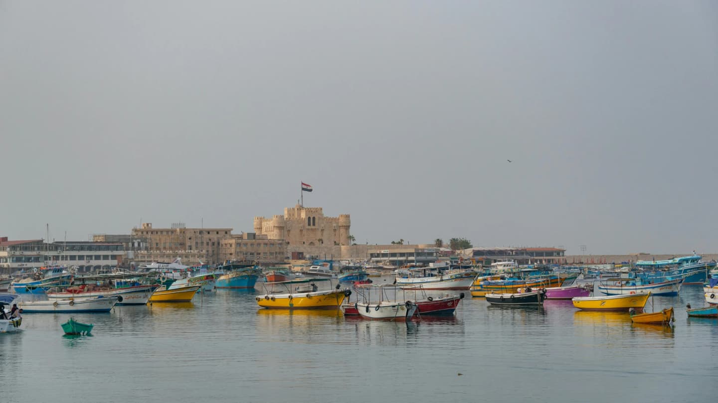 Soma Bay, Egypt - Colorful boats float in alexandria's harbor with the historic citadel of qaitbay in the background.