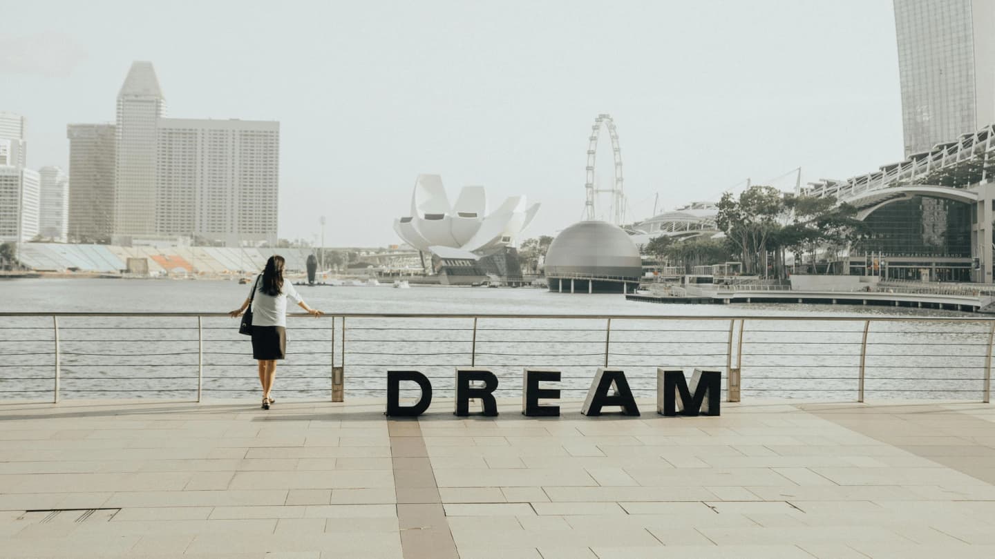 Soma Bay, Egypt - Woman gazing at the iconic marina bay sands skyline in singapore with 'dream' letters foregrounded.