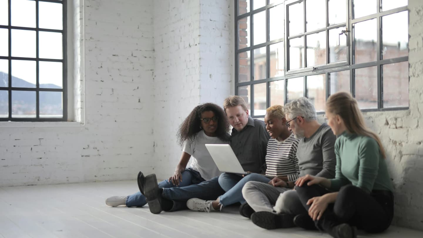 Soma Bay, Egypt - Diverse group of professionals having a casual meeting with a laptop in a bright, modern room.