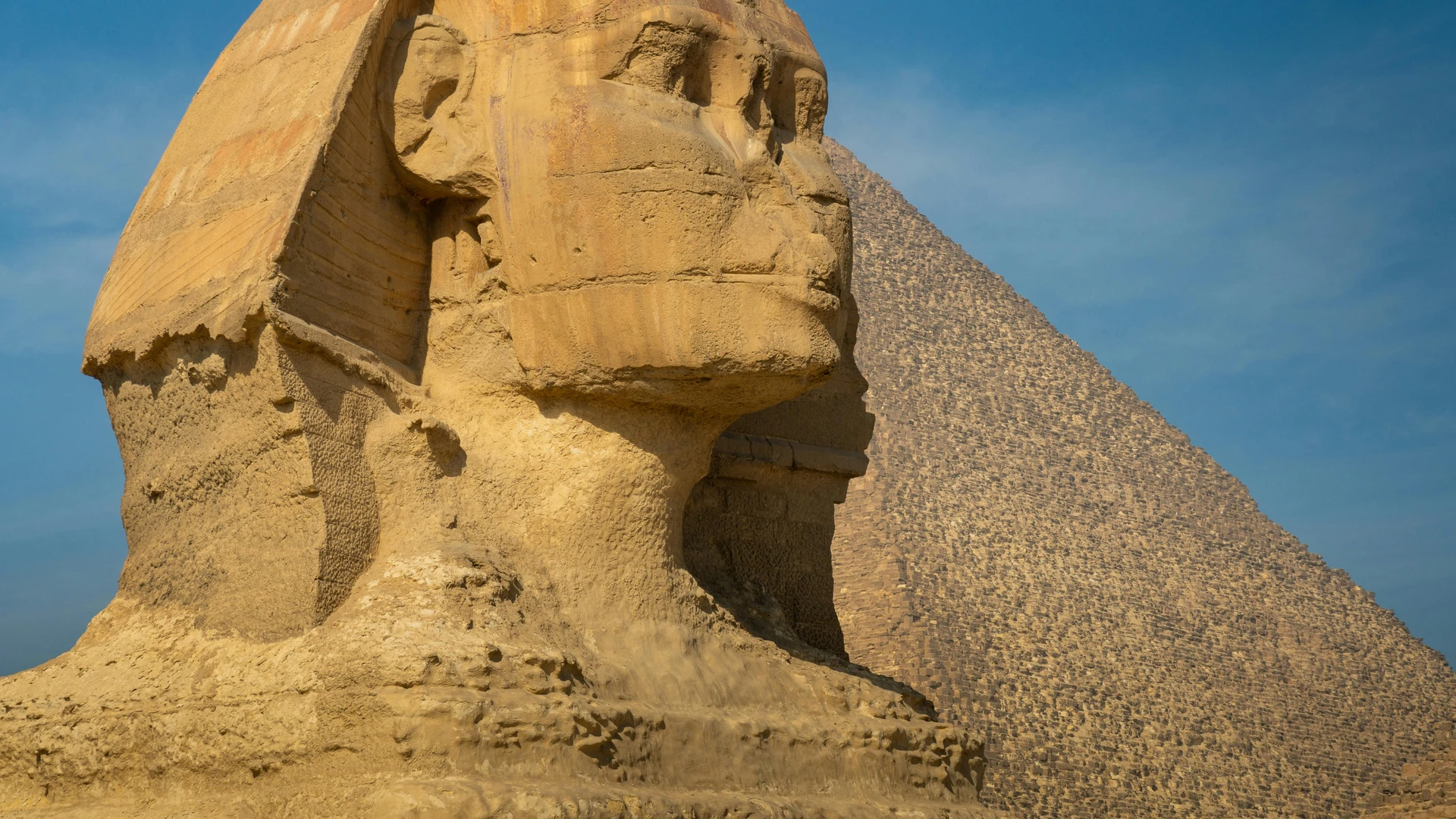 El Alamein, Egypt - Iconic view of the great sphinx of giza beside a pyramid under a clear blue sky.