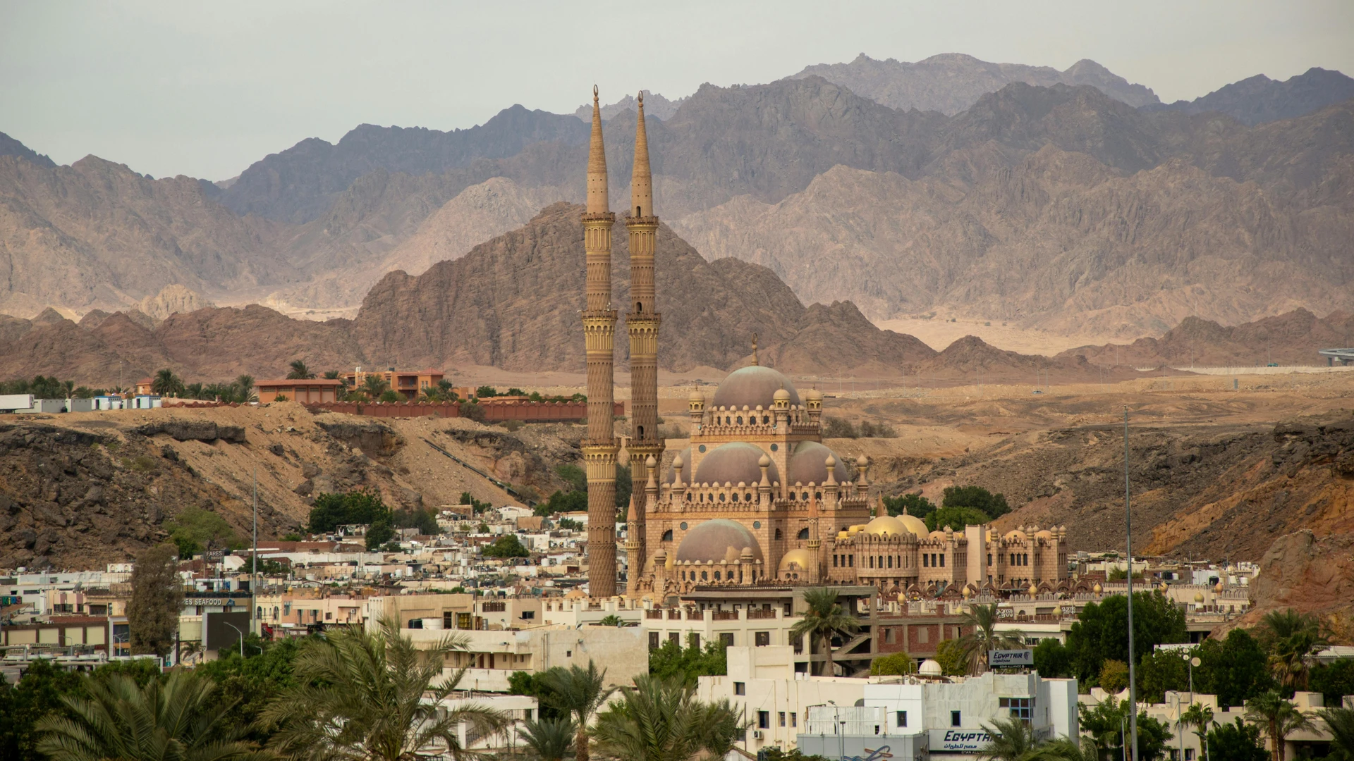 El Alamein, Egypt - Grand mosque with tall minarets in sharm el sheikh set against desert mountains.