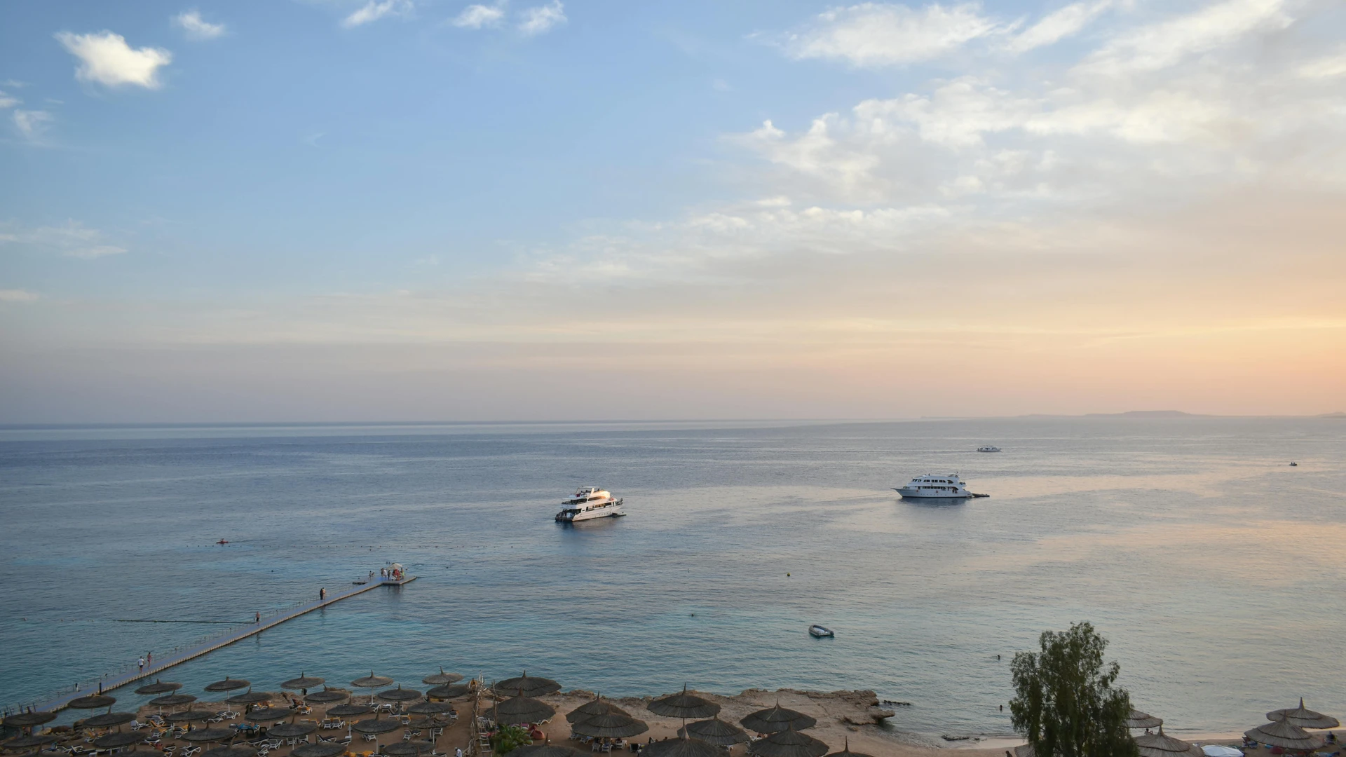 El Alamein, Egypt - Stunning aerial view of sharm el sheikh's beach and sea during sunset with boats and parasols.